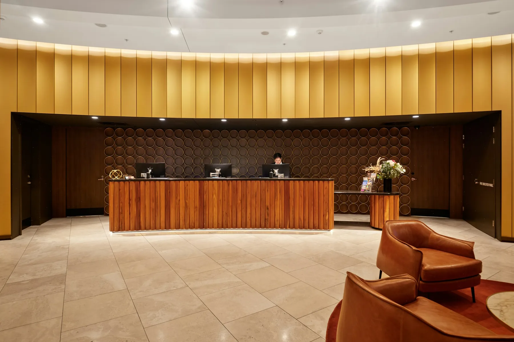 After: reception area with a curved fluted gold feature wall and timber desk
